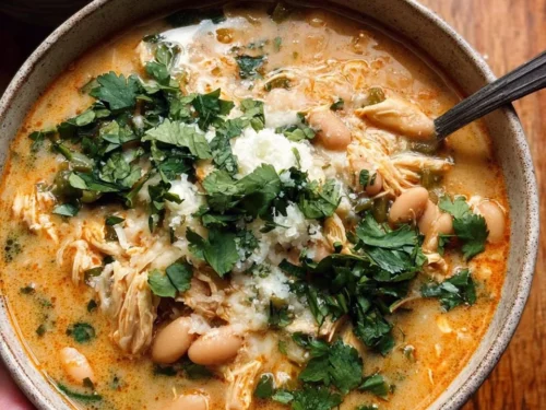 Bowl of creamy white chicken chili garnished with cilantro and lime