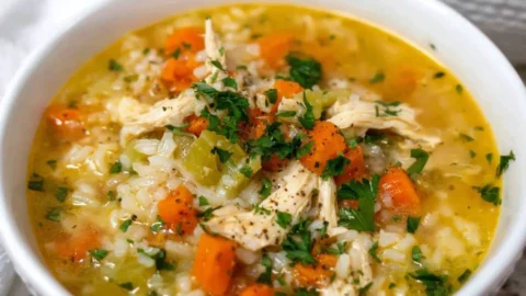 Bowl of delicious homemade Chicken Rice Soup garnished with herbs.