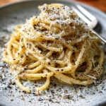 Bowl of gluten-free cacio e pepe with cheese and pepper seasoning