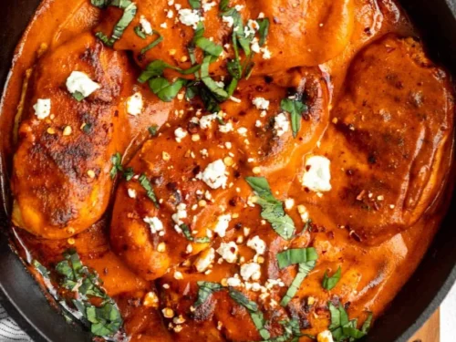 Juicy Roasted Red Pepper Chicken garnished with herbs and served on a plate.